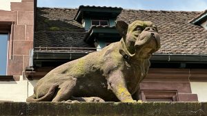 Dog statue above a pole on a wall next to a church