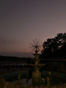 A decorative fountain with a starburst design sits at the center, illuminated by soft lighting.
