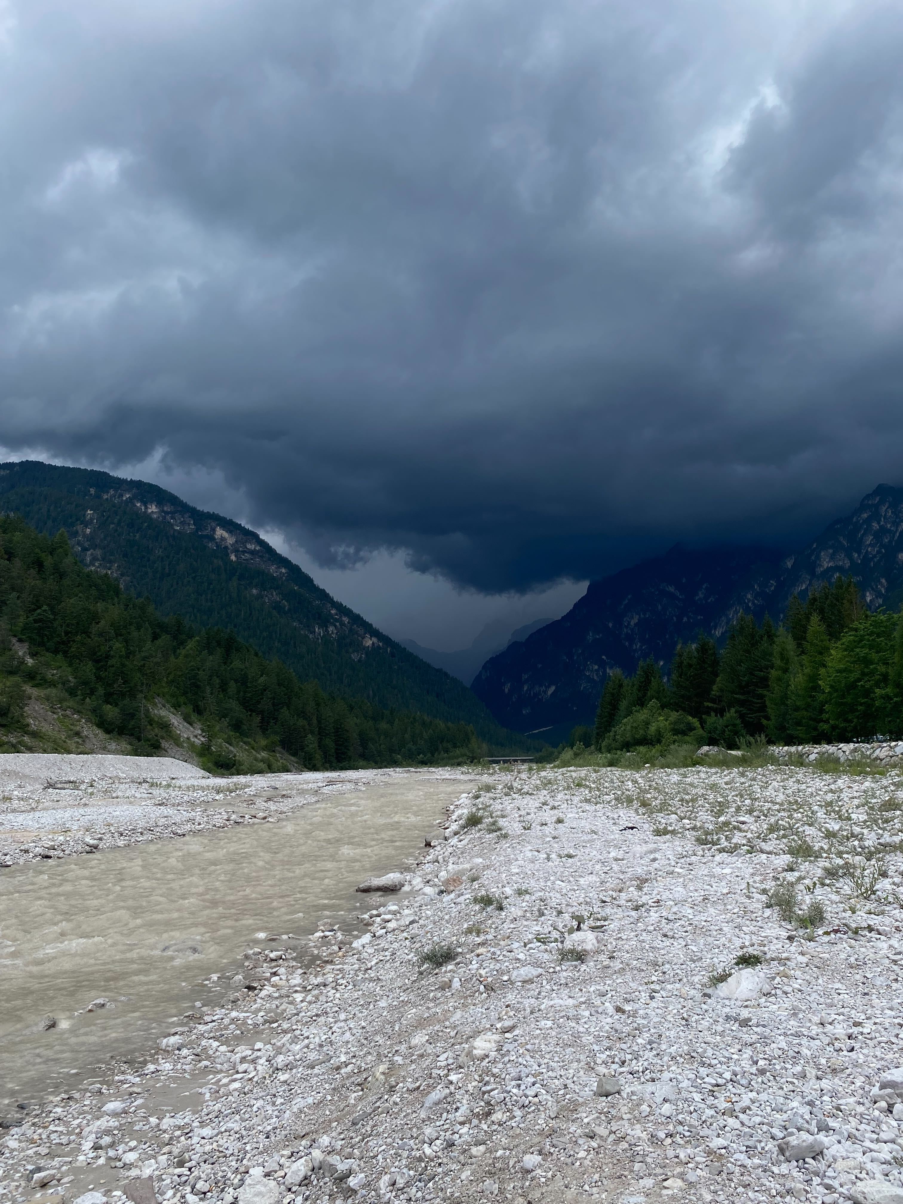 River in Italy, next to the Dolomites, with a dark sky before a storm