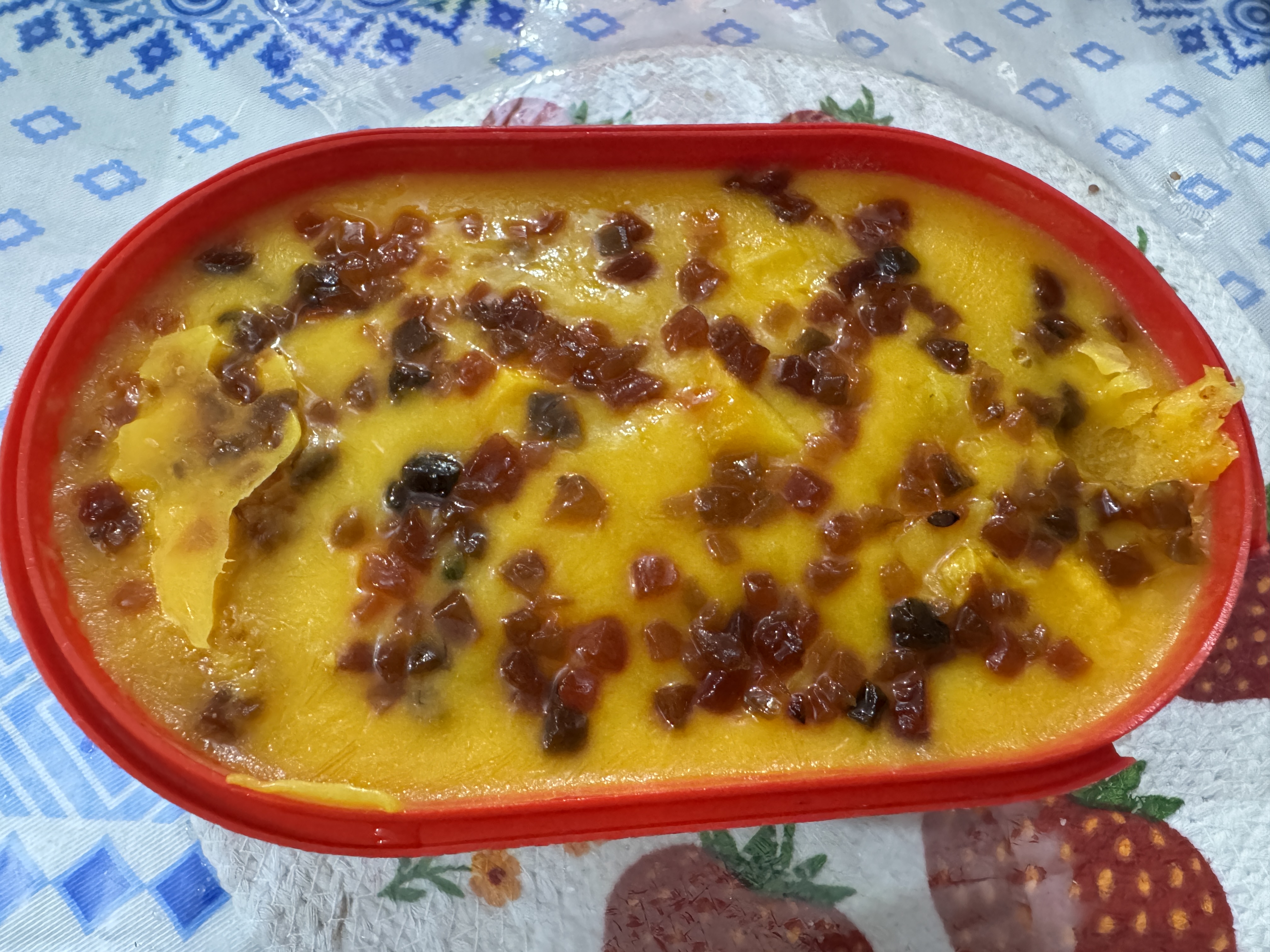 A tub of mango ice cream topped with small pieces of dried fruit.