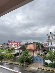 A view from a balcony showing a neighborhood under a cloudy sky. 