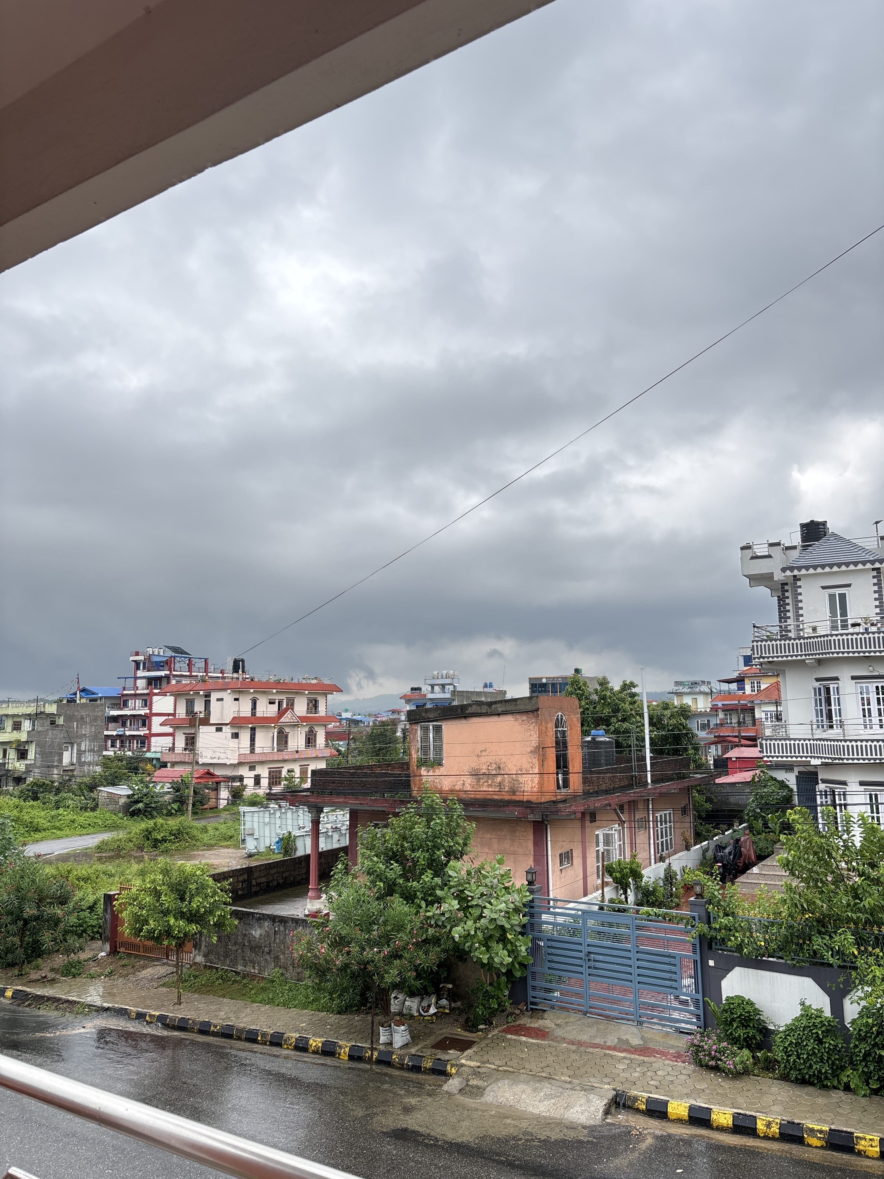 A view from a balcony showing a neighborhood under a cloudy sky.