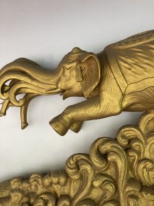 Golden sculpture of an elephant with intricate features, including ornate decorations on its head and a textured body.
