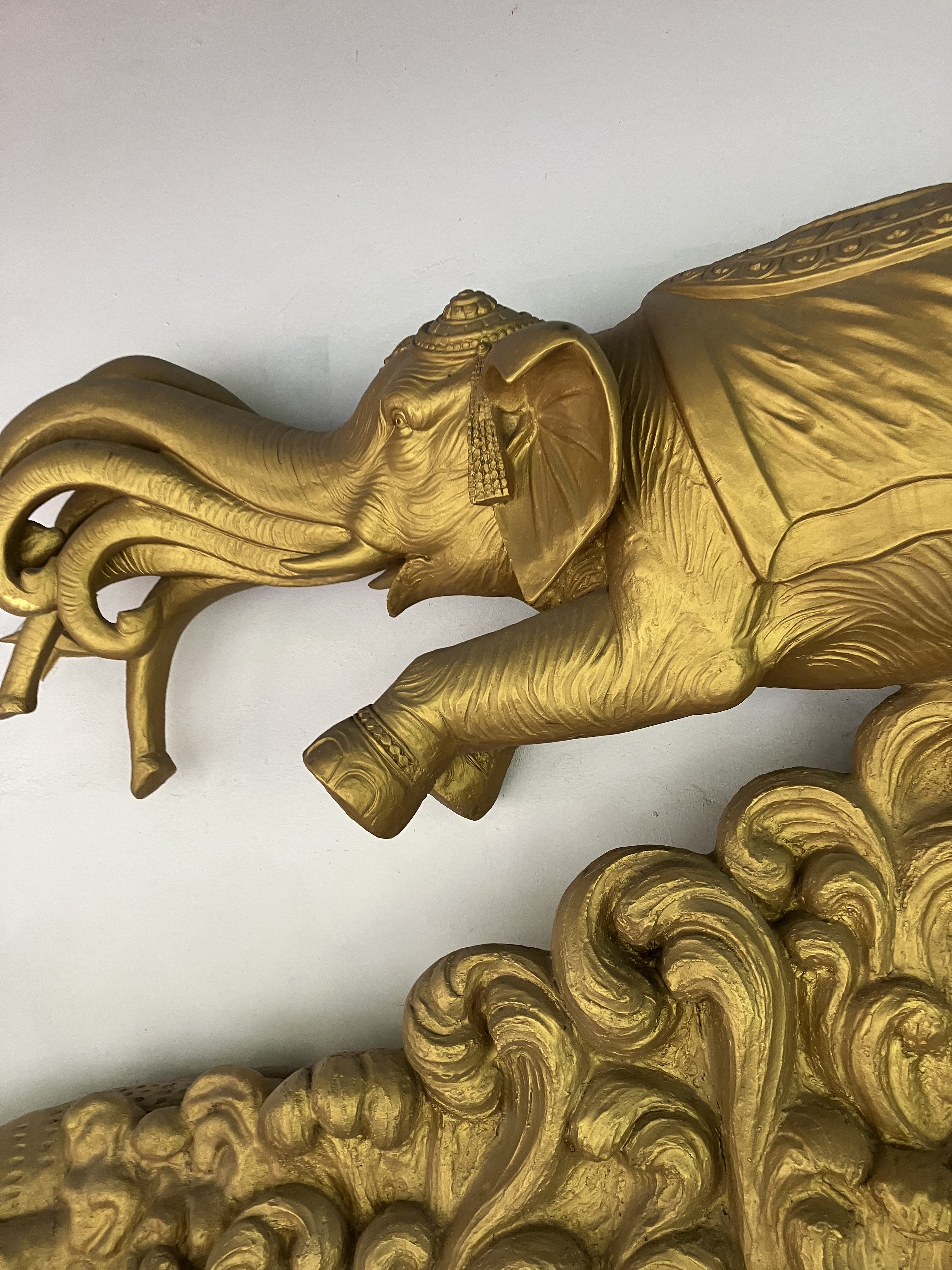 Golden sculpture of an elephant with intricate features, including ornate decorations on its head and a textured body.