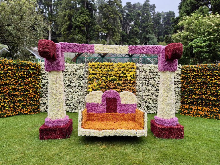 A colorful floral swing and backdrop at the Ooty Flower Show in Tamil Nadu, India, creating a vibrant and festive display.