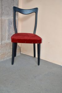 A red velvet chair with a dark frame sits indoors against a neutral wall and stone surface, captured in Tenerife, Spain.