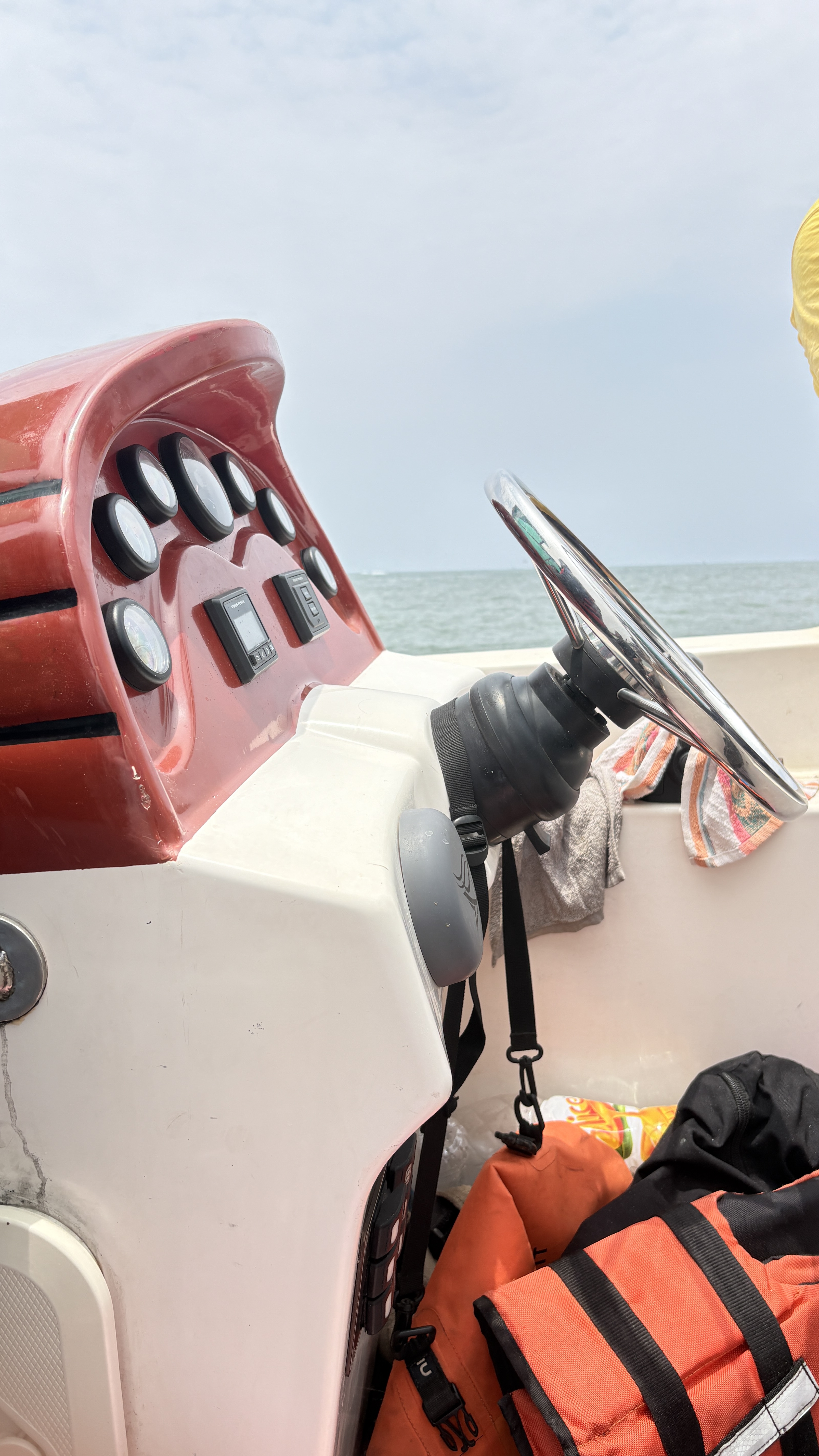 A close-up view of a boat's control panel featuring a steering wheel, various gauges, and switches.