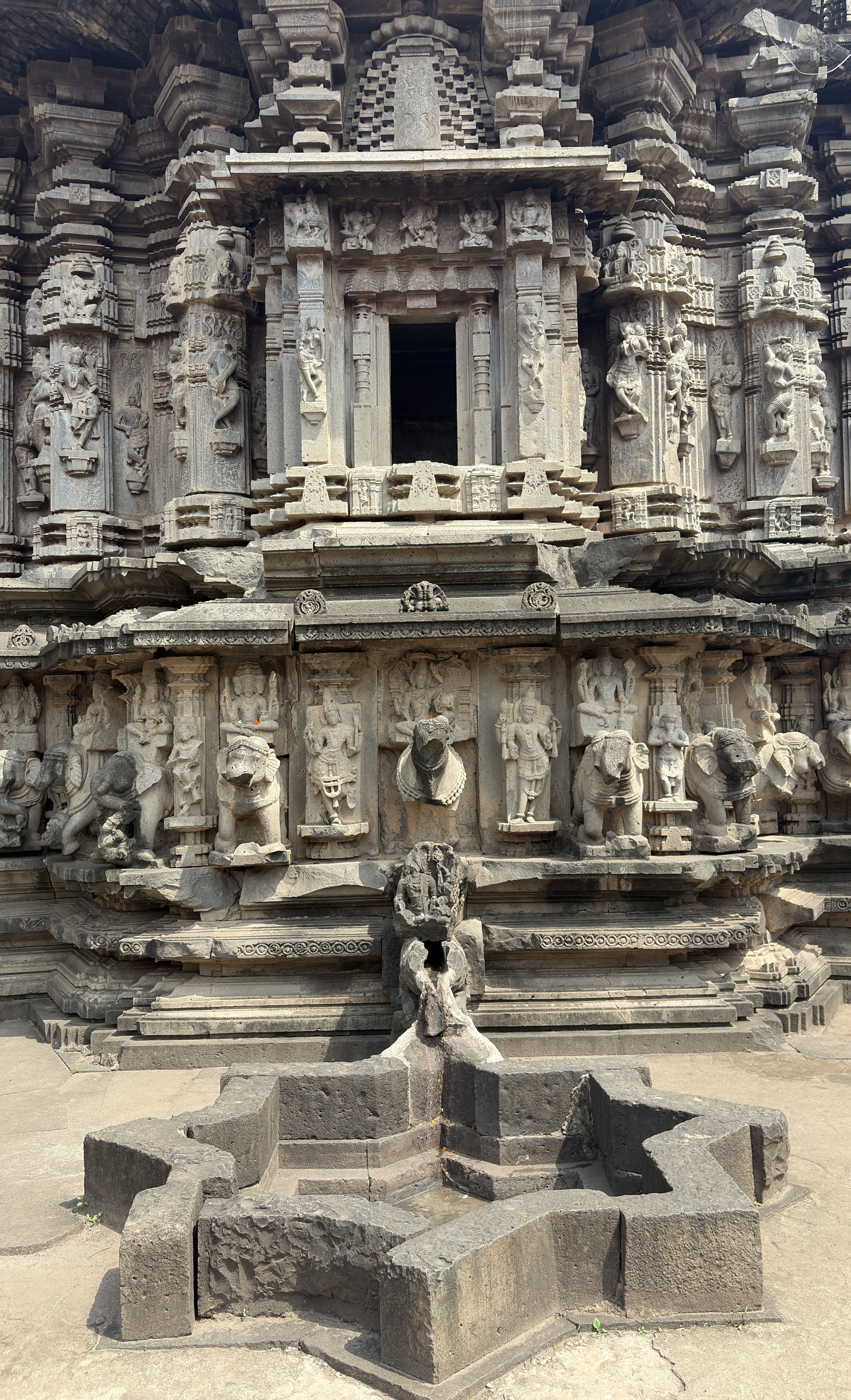 A close-up view of an intricately carved stone temple façade featuring several figures and ornamental details.
