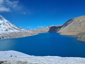 A stunning landscape of Tilicho Lake, its deep blue waters framed by rugged mountains.
