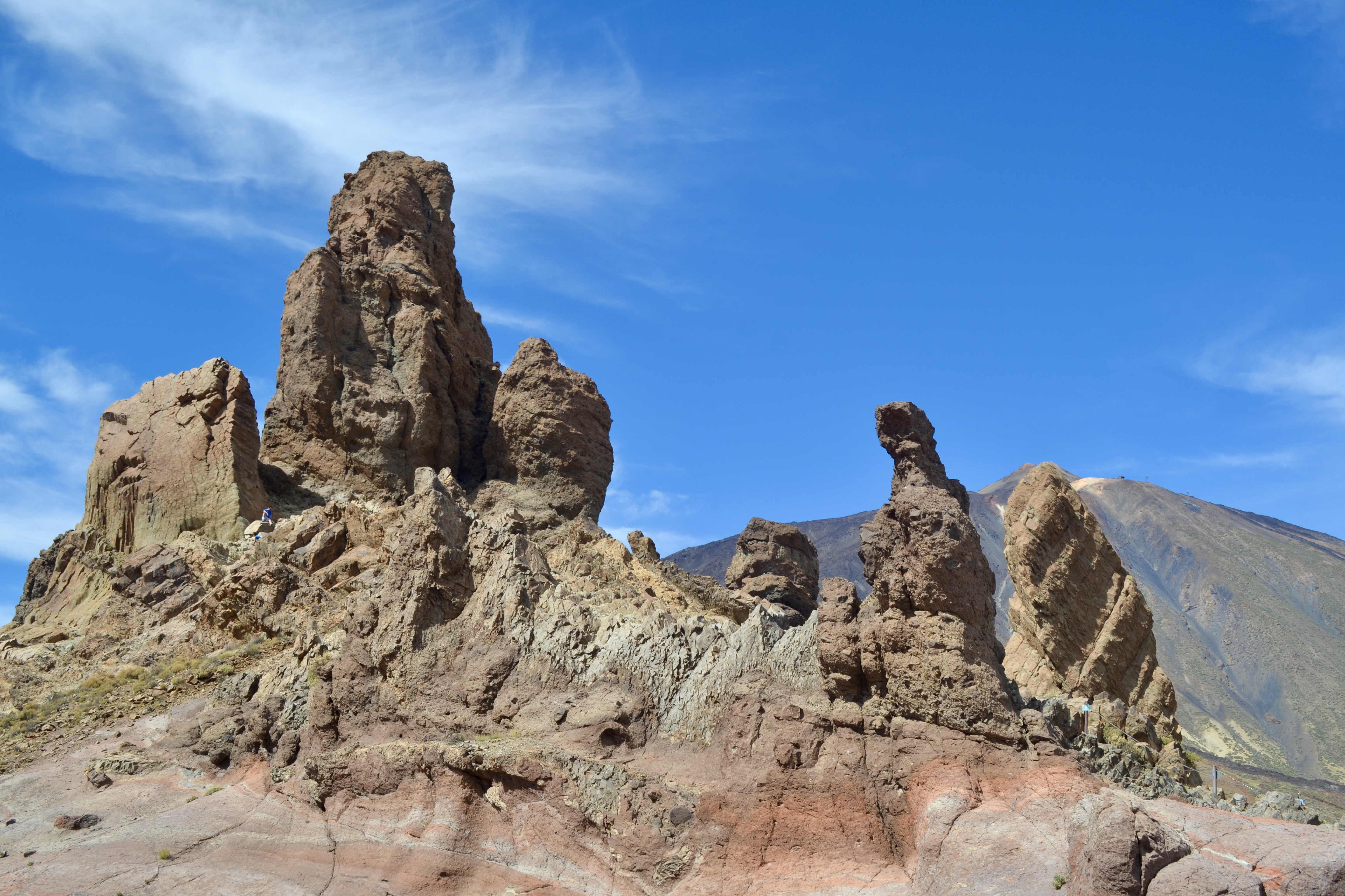 The volcanic landscape of Teide National Park in Tenerife. In the front, you can see the large rocks called Roques de García. In the background, Mount Teide, the tallest mountain in Spain, stands under a clear blue sky.