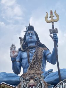 A large statue of a blue-skinned deity is depicted, seated in a meditative pose. 