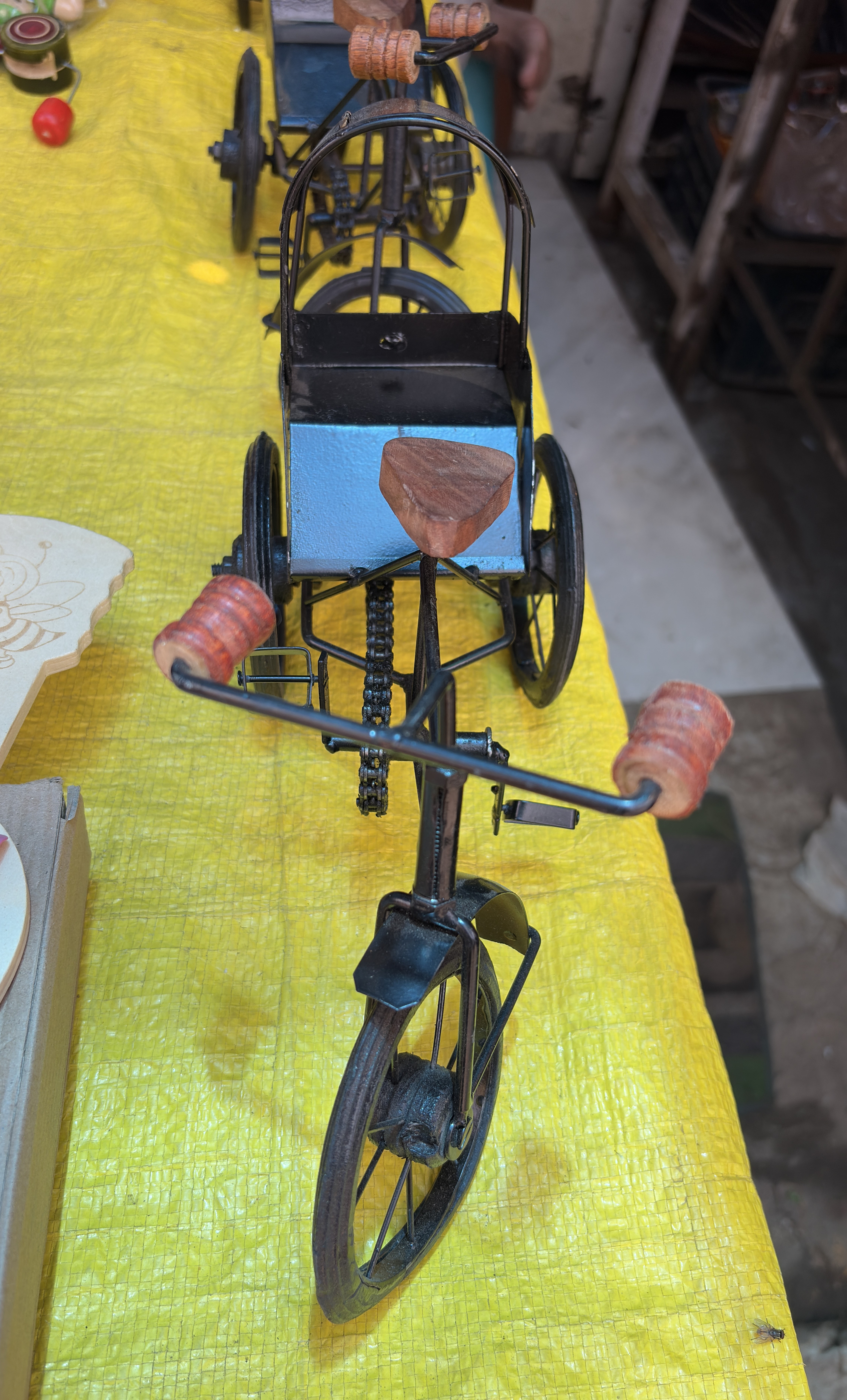 A close-up view of a decorative model of a cycle rickshaw made from metal.