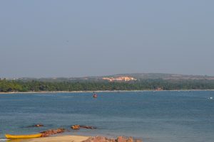 A coastal scene featuring a calm blue sea with boats scattered on the water. 