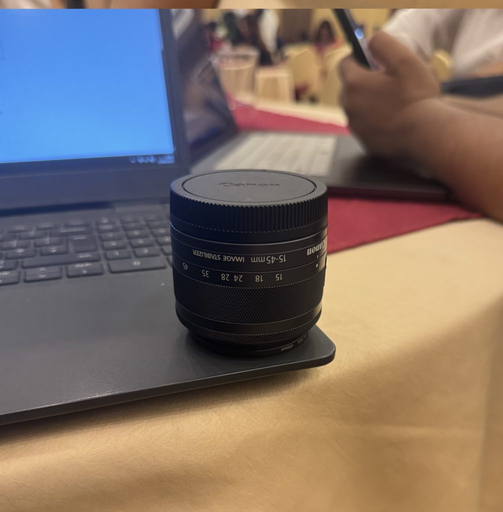 Camera lens sitting on a laptop at tabletop.
