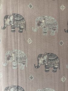 A patterned fabric featuring elephants in various poses, intricately designed with mandala-like details