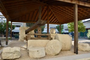 An ancient olive press with stone and wood elements, sheltered in Limassol, Cyprus.