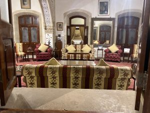 A cozy sitting room featuring a mix of upholstered furniture, including floral-patterned sofas and armchairs with decorative cushions. 