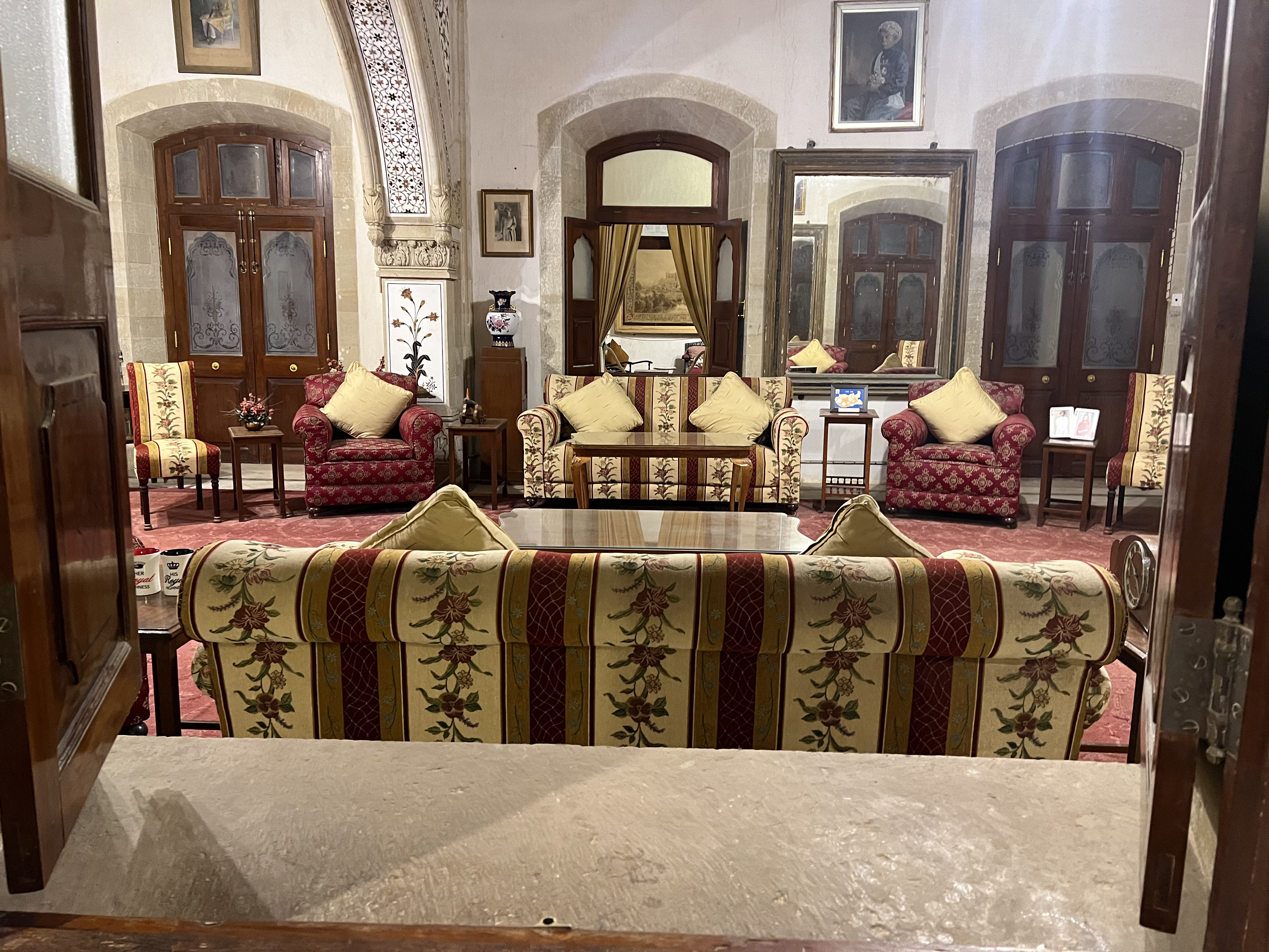 A cozy sitting room featuring a mix of upholstered furniture, including floral-patterned sofas and armchairs with decorative cushions.