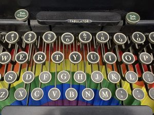 Rainbow fan sitting under black old fashioned typewriter keyboard keys.