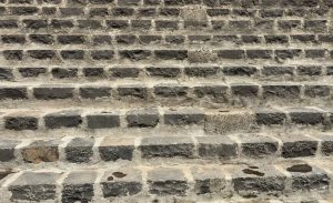 A close-up view of stone steps showing uneven, textured surfaces with visible wear and tear. 