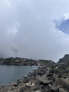 A serene landscape featuring a calm lake surrounded by rocky terrain and patches of greenery