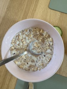 A bowl of muesli soaked in milk, featuring a mix of oats, grains, and seeds, served with a spoon for a wholesome and simple breakfast.