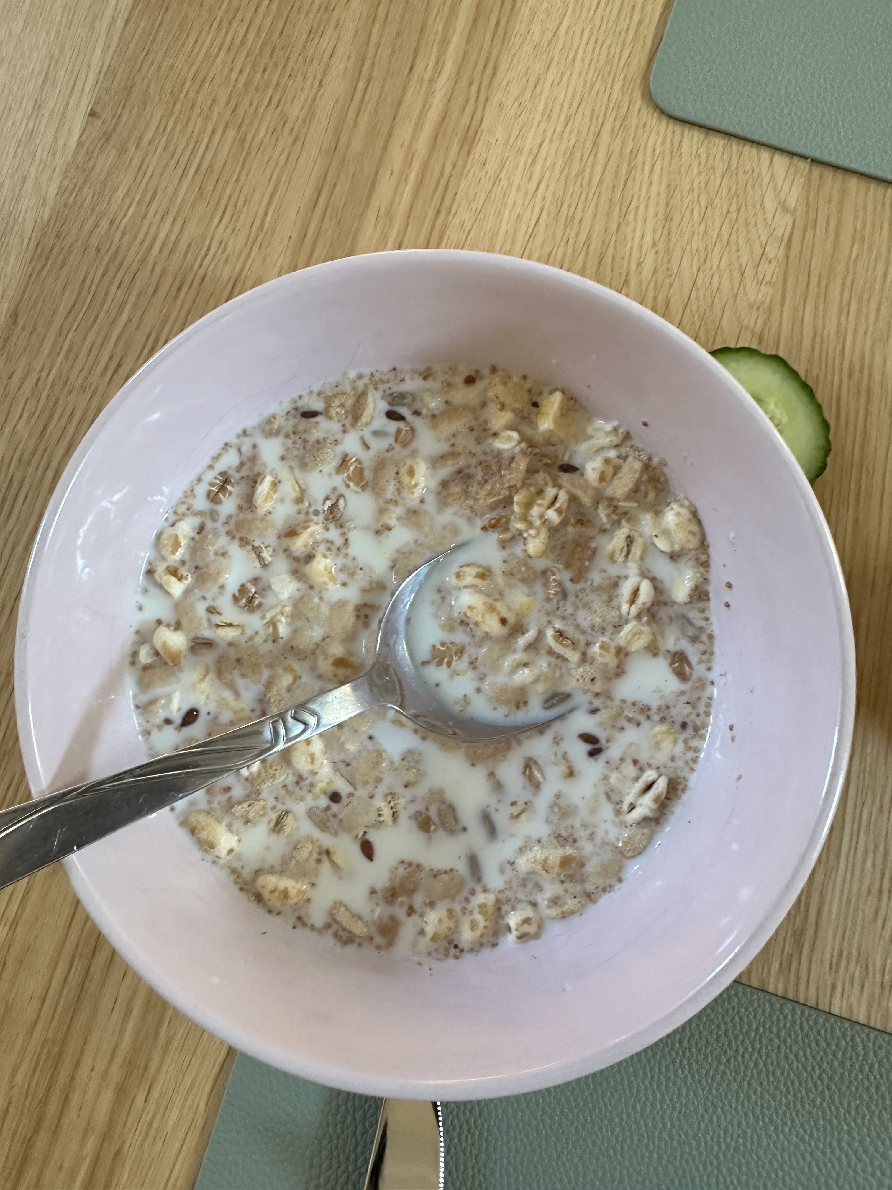 A bowl of muesli soaked in milk, featuring a mix of oats, grains, and seeds, served with a spoon for a wholesome and simple breakfast.