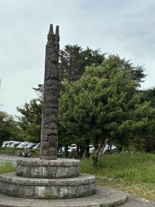 千葉ポートパーク　トーテムポール　/　A picture of Chiba Port Park Totem Pole which looks artistic through indigenous carving in it. Its background contains bushes and trees.