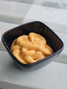 Creamy orange mayo in a black bowl, a perfect dip from Kozhikode, Kerala.