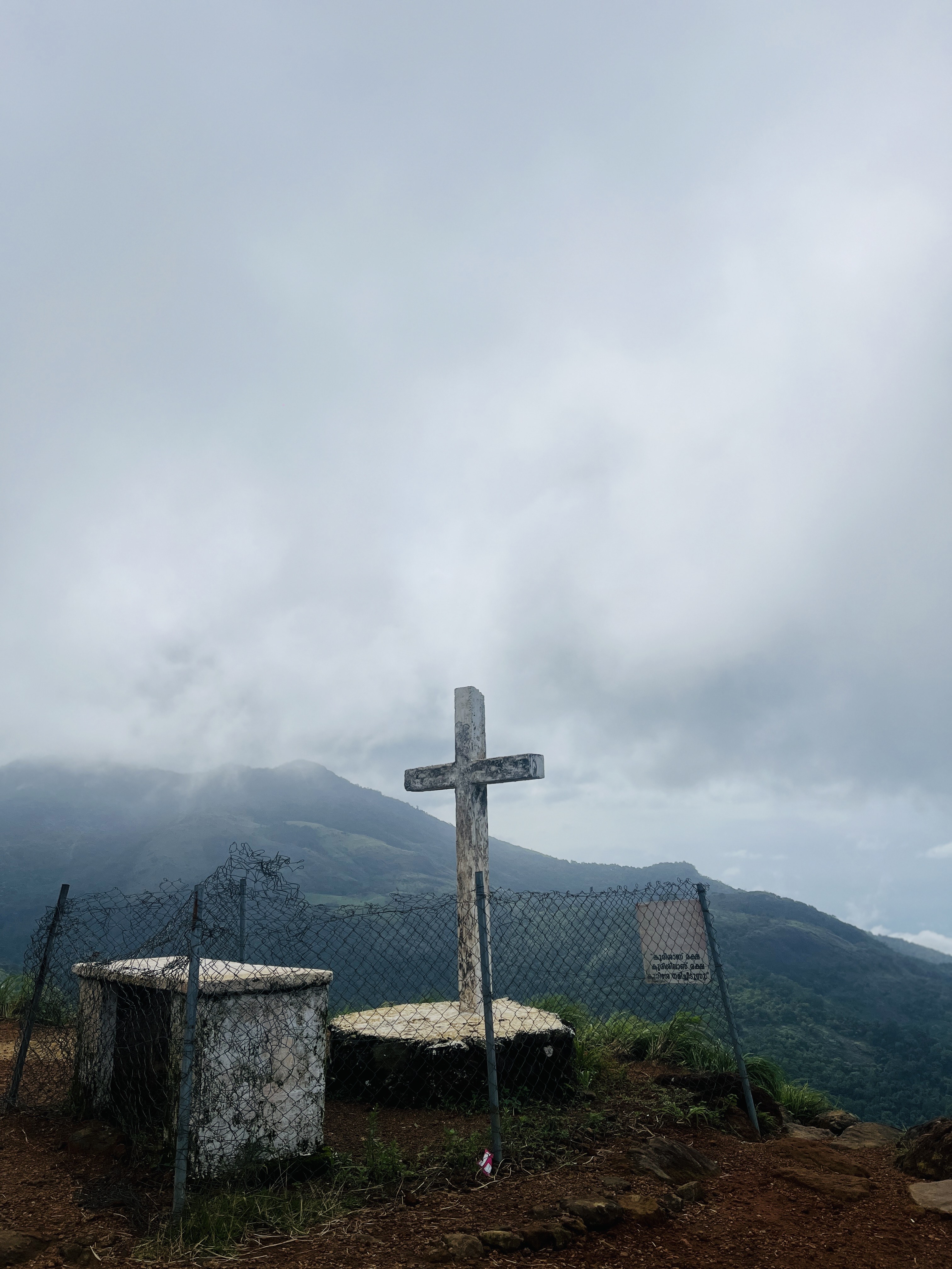 A cross on top of a hill next to a fence. Photo taken at kurishumala, Kerala