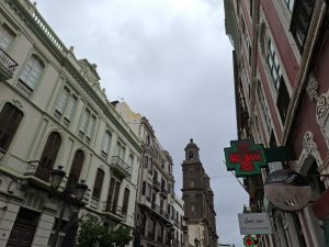 A narrow street lined with elegant buildings in pastel shades, featuring decorative architectural details. 