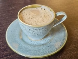 A frothy South Indian filter coffee served in a ceramic cup, enjoyed in Kozhikode, Kerala.