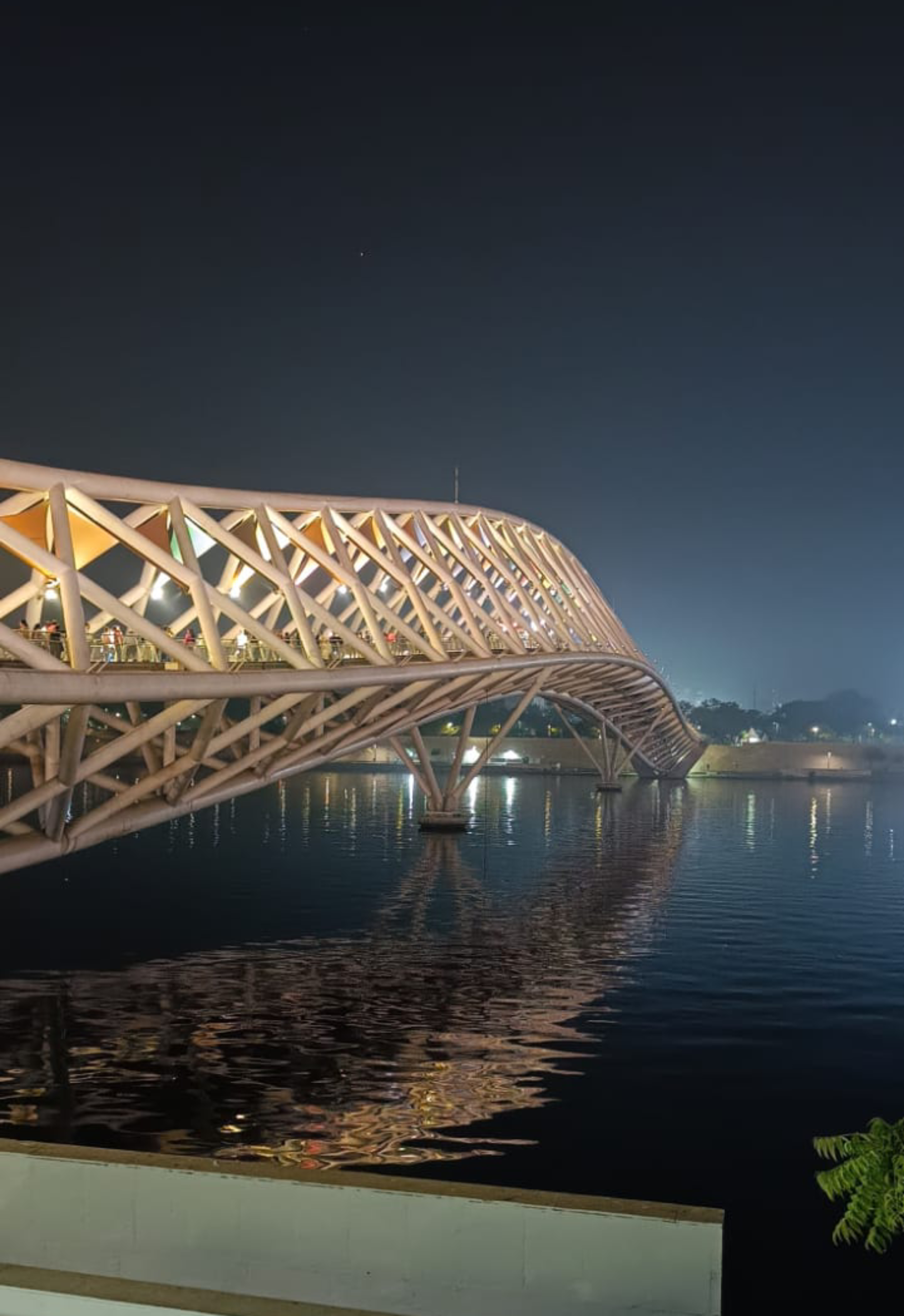 Atal Pedestrian Bridge glowing at night over the Sabarmati River in Ahmedabad.