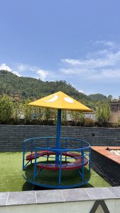 A colorful children's play structure with a yellow canopy featuring a sun and moon design, sitting on a grassy area.