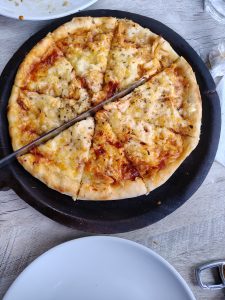 A freshly baked pizza on a wooden serving board, sliced into six equal pieces.