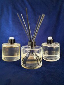 Three clear glass diffuser bottles are placed on a dark blue background. 