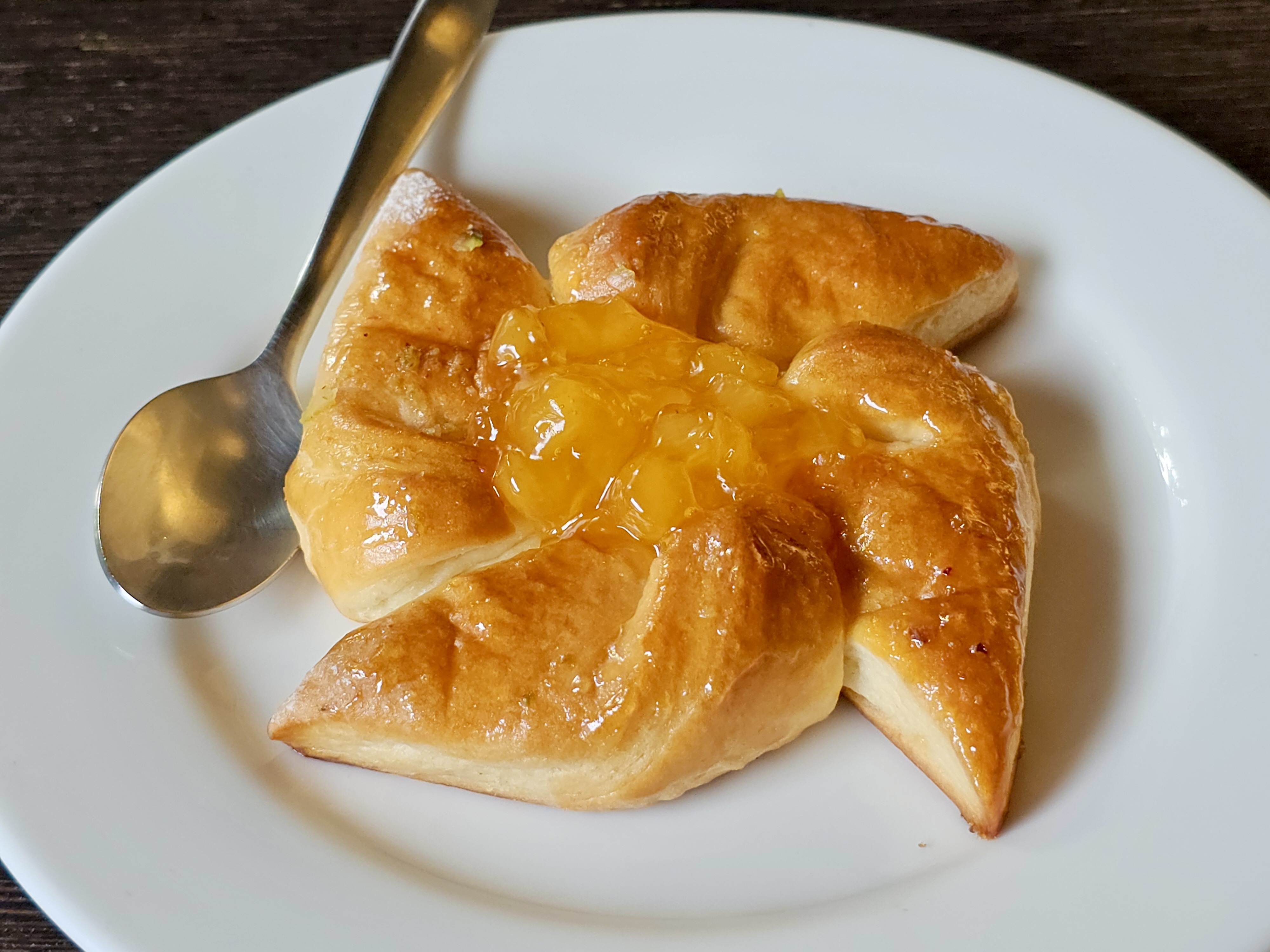 A glossy Danish pastry with fruit jam, served on a plate in Kozhikode.