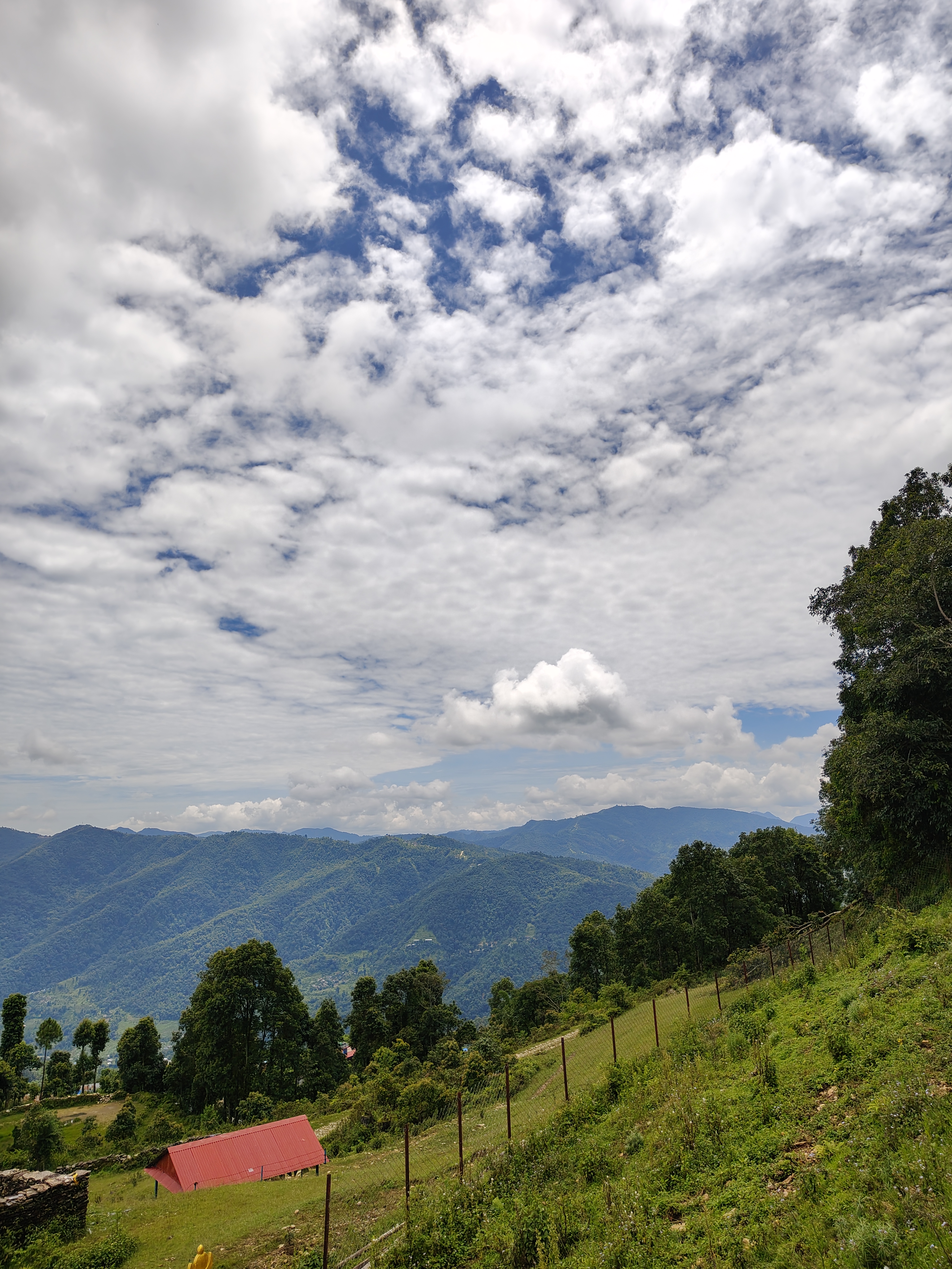 A scenic view of rolling green hills and mountains under a partly cloudy sky.