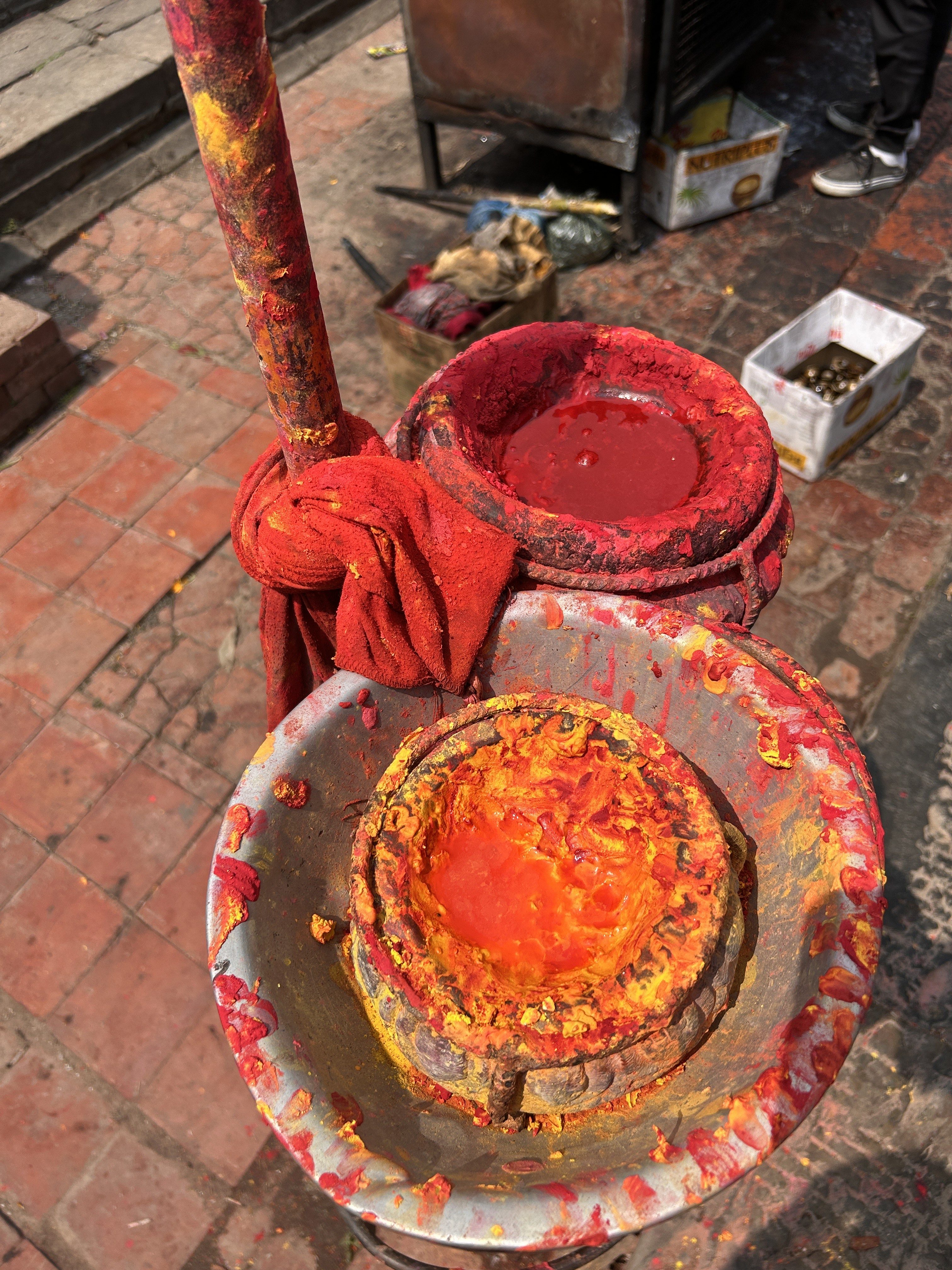 A close-up view of two small containers filled with vibrant red and orange powders, typically used for religious or cultural ceremonies. 