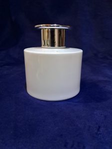 A white cylindrical bottle with a shiny metallic pump top, set against a dark blue background
