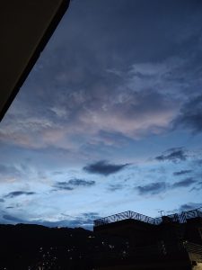 A panoramic view of a twilight sky, with shades of blue and hints of pink among the clouds.
