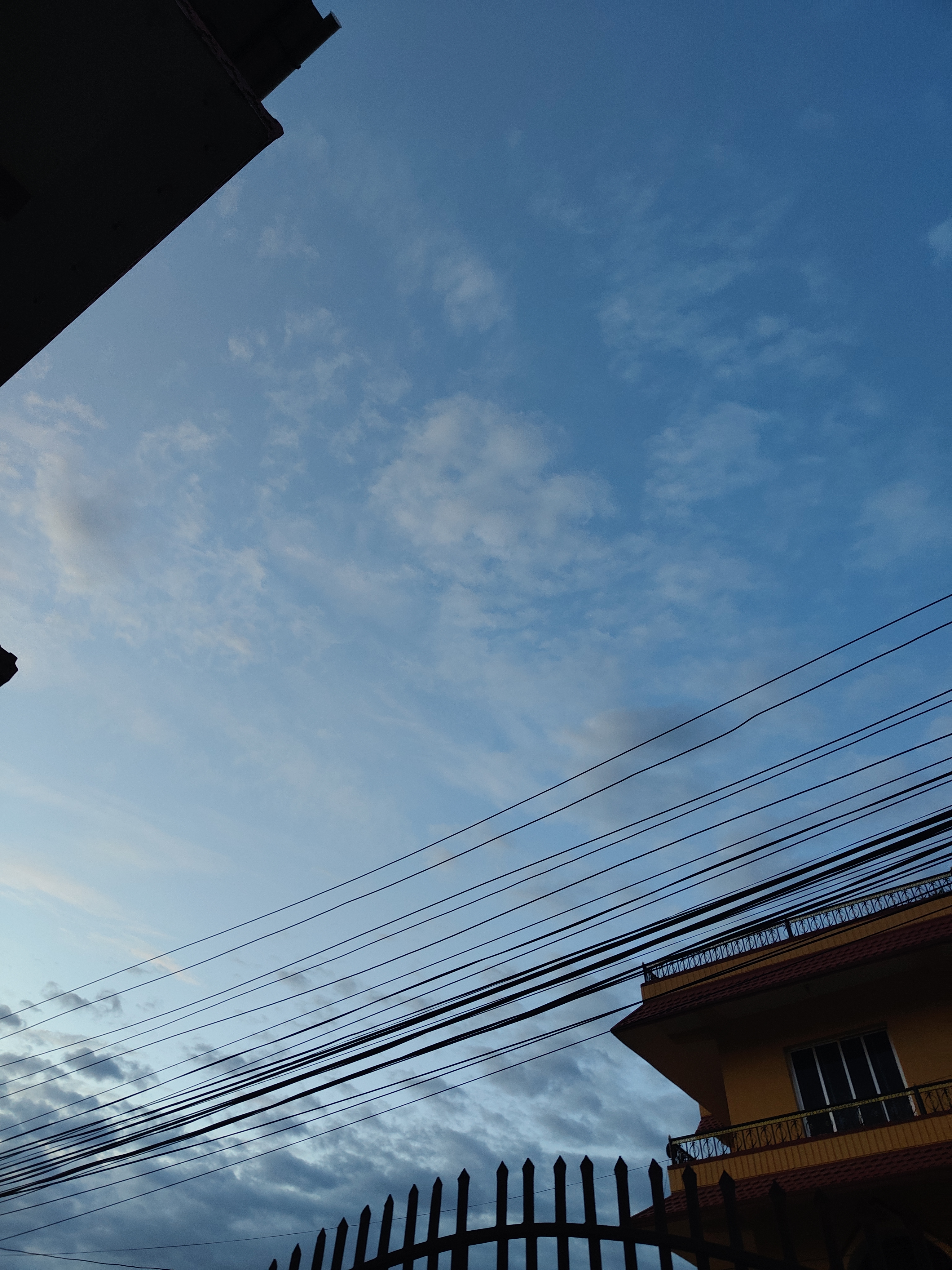 A view of the sky taken from a low angle, featuring a gradient of blue and wispy clouds.
