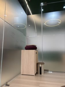 A modern, minimalist interior space featuring a wooden cabinet with a door on the left side. 