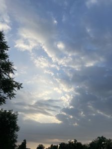 A partially cloudy sky with soft, fluffy clouds scattered across a blue backdrop.
