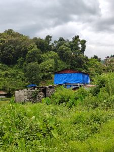 A landscape featuring a hillside covered in lush greenery and trees under a cloudy sky.