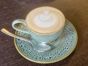 A latte with heart-shaped foam art in a ceramic cup, from a Kozhikode café