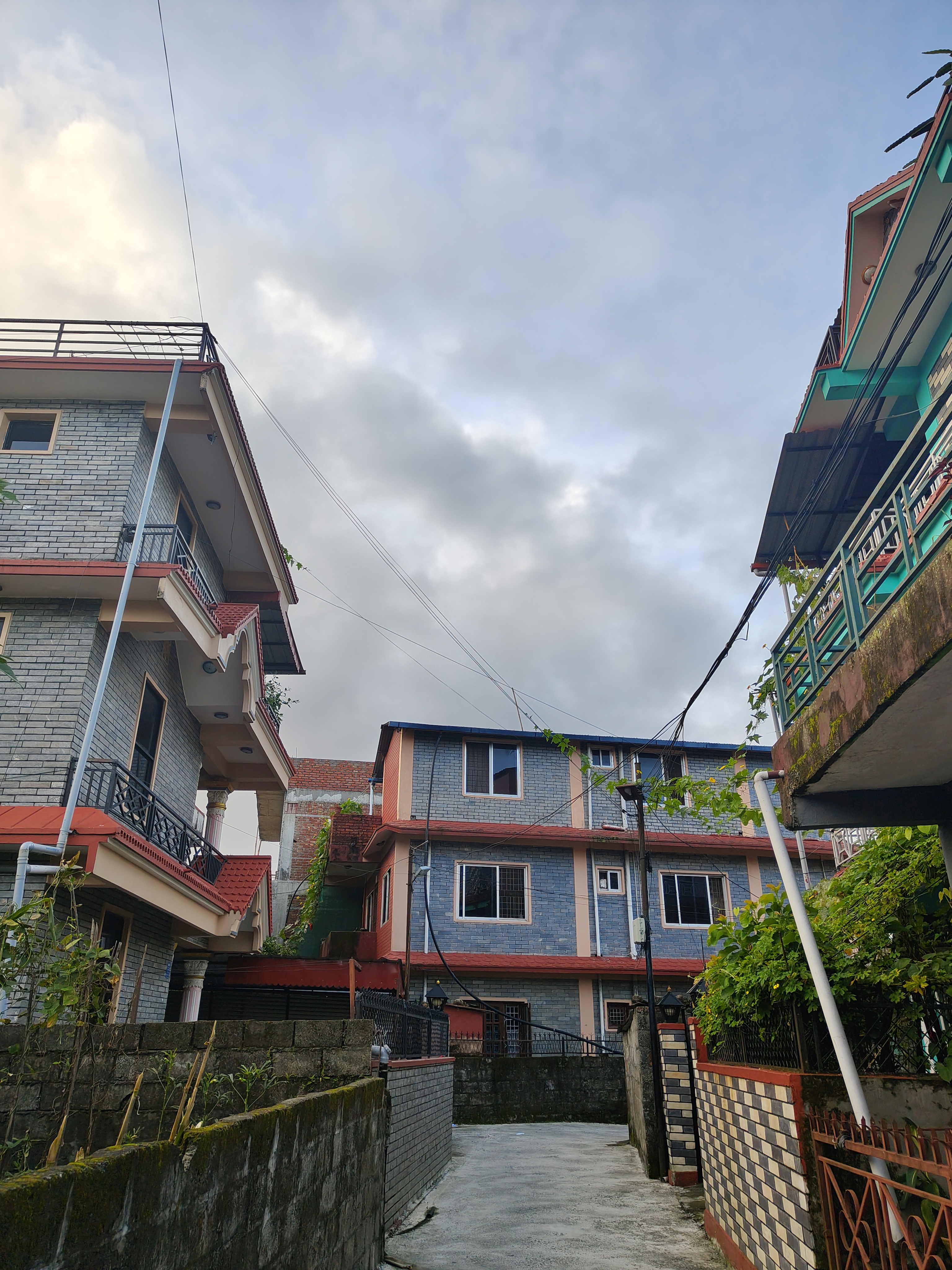 The image shows a narrow pathway flanked by two multi-story buildings with a mix of stone and painted facades.