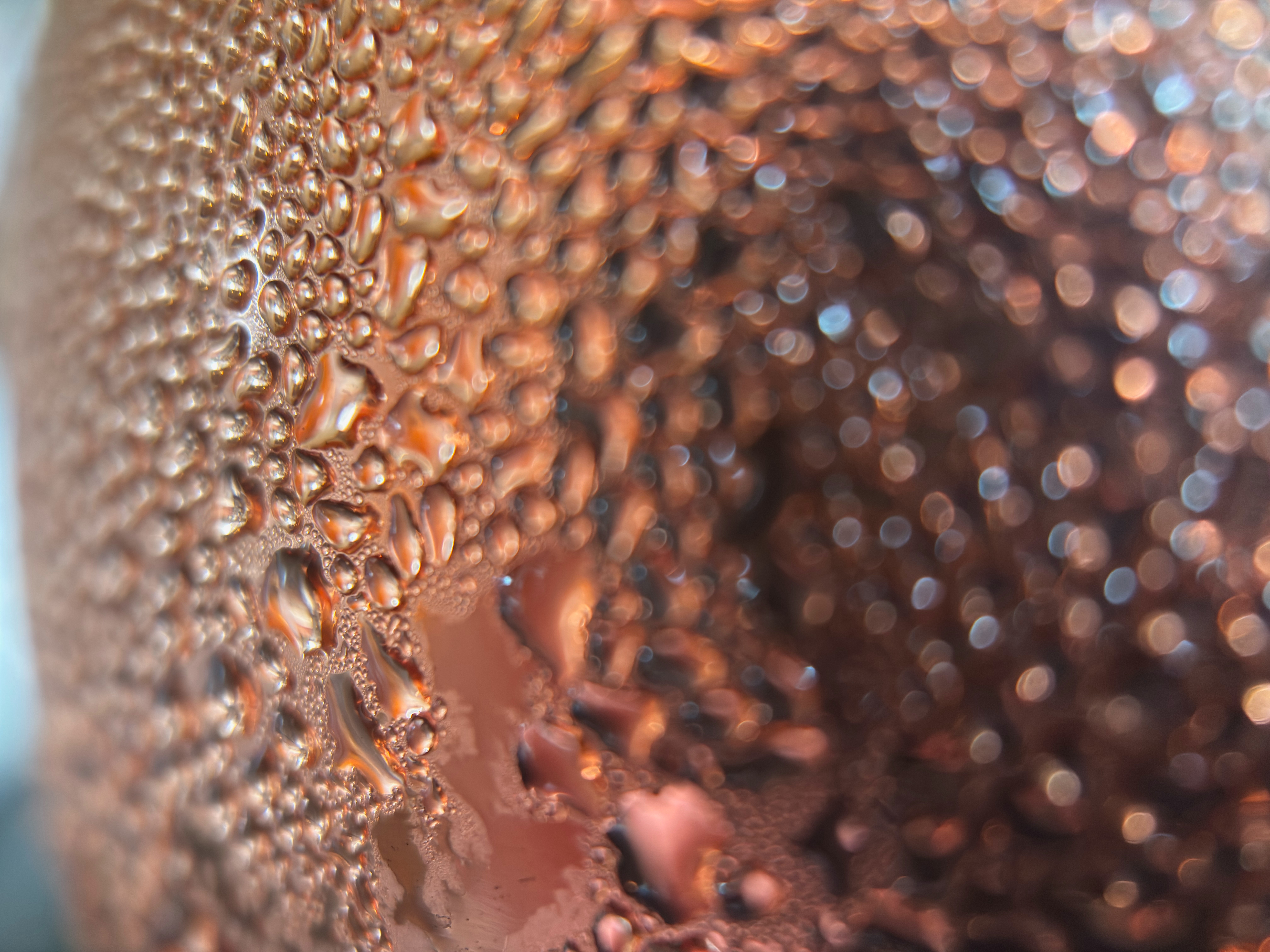 Closeup of water droplets on the side of a copper mug.
