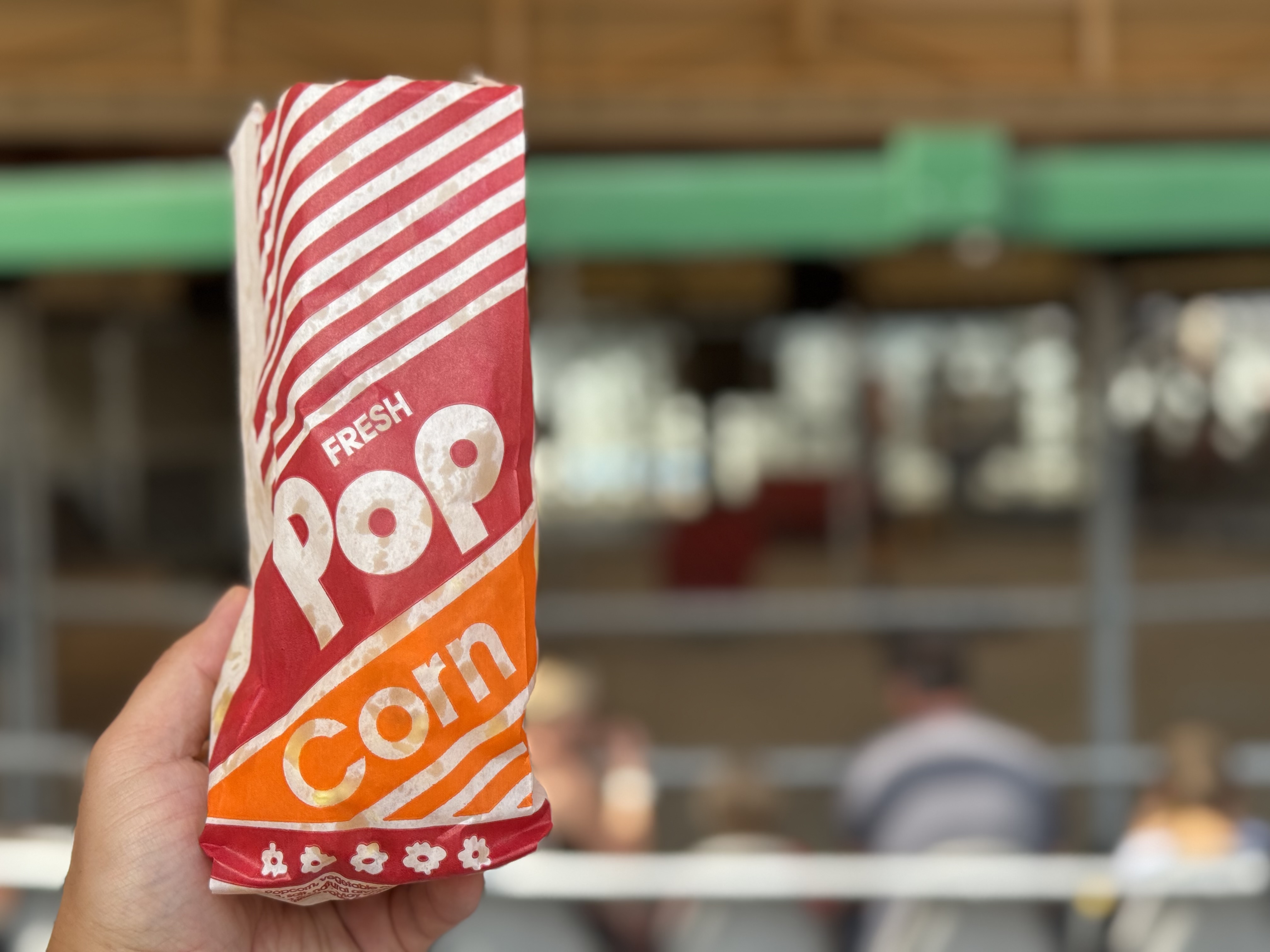 A personal-sized bag of fresh popcorn held up at an event.