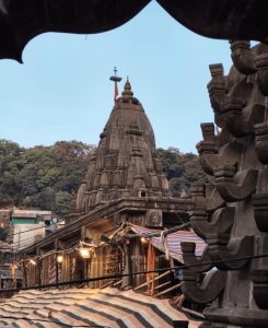 Bhimashankar Temple, one of five Jyotirlingas of Maharashtra, dedicated to Mahadev. Conical shaped, covered in carvings, under a blue sky.